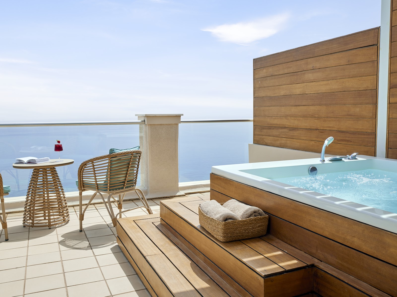 Private terrace with hot tub, rattan chair, and sea views at MarBella resort.