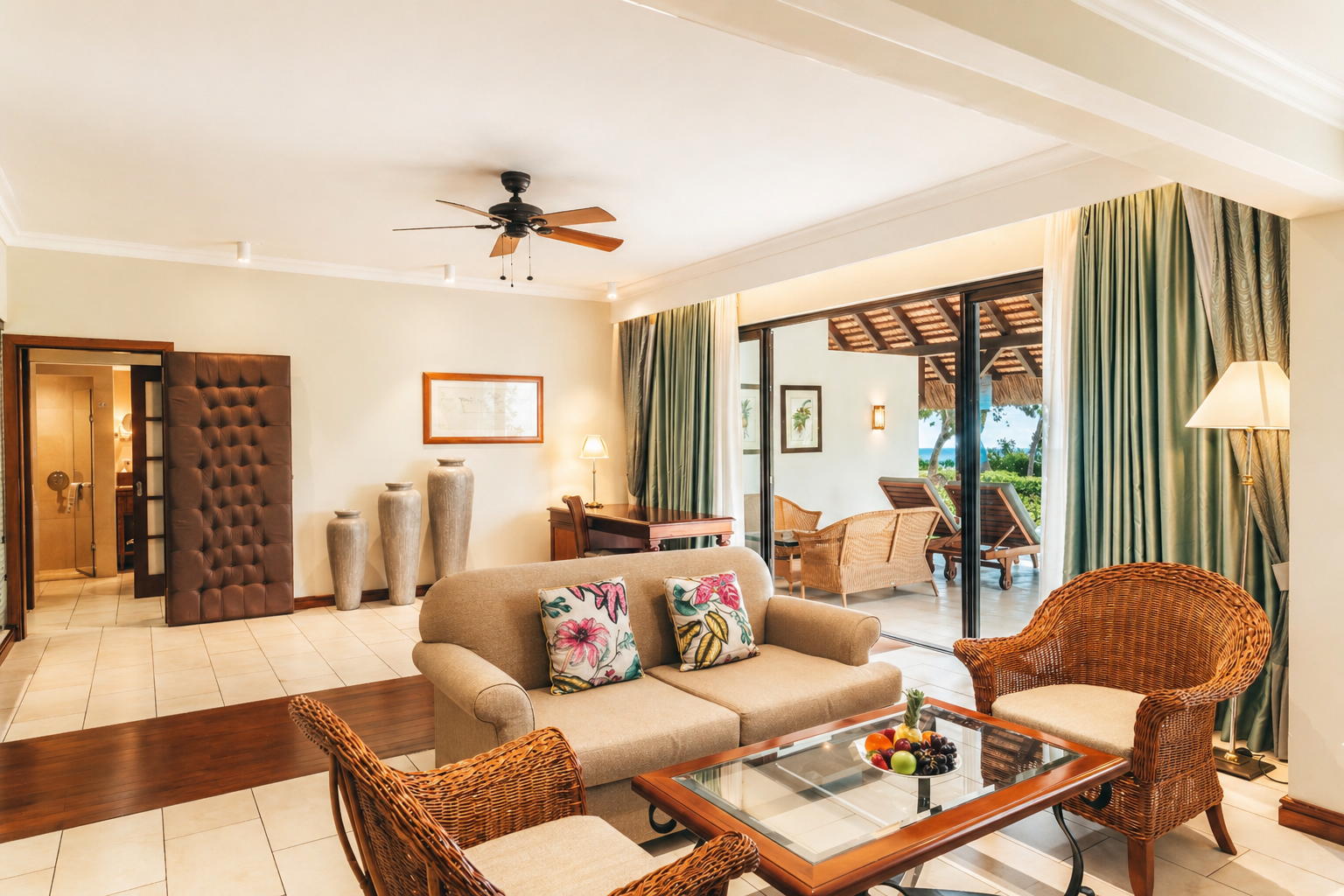 Spacious resort bedroom with white bed, terracotta accent wall, and ocean view through sliding glass doors opening to a balcony.