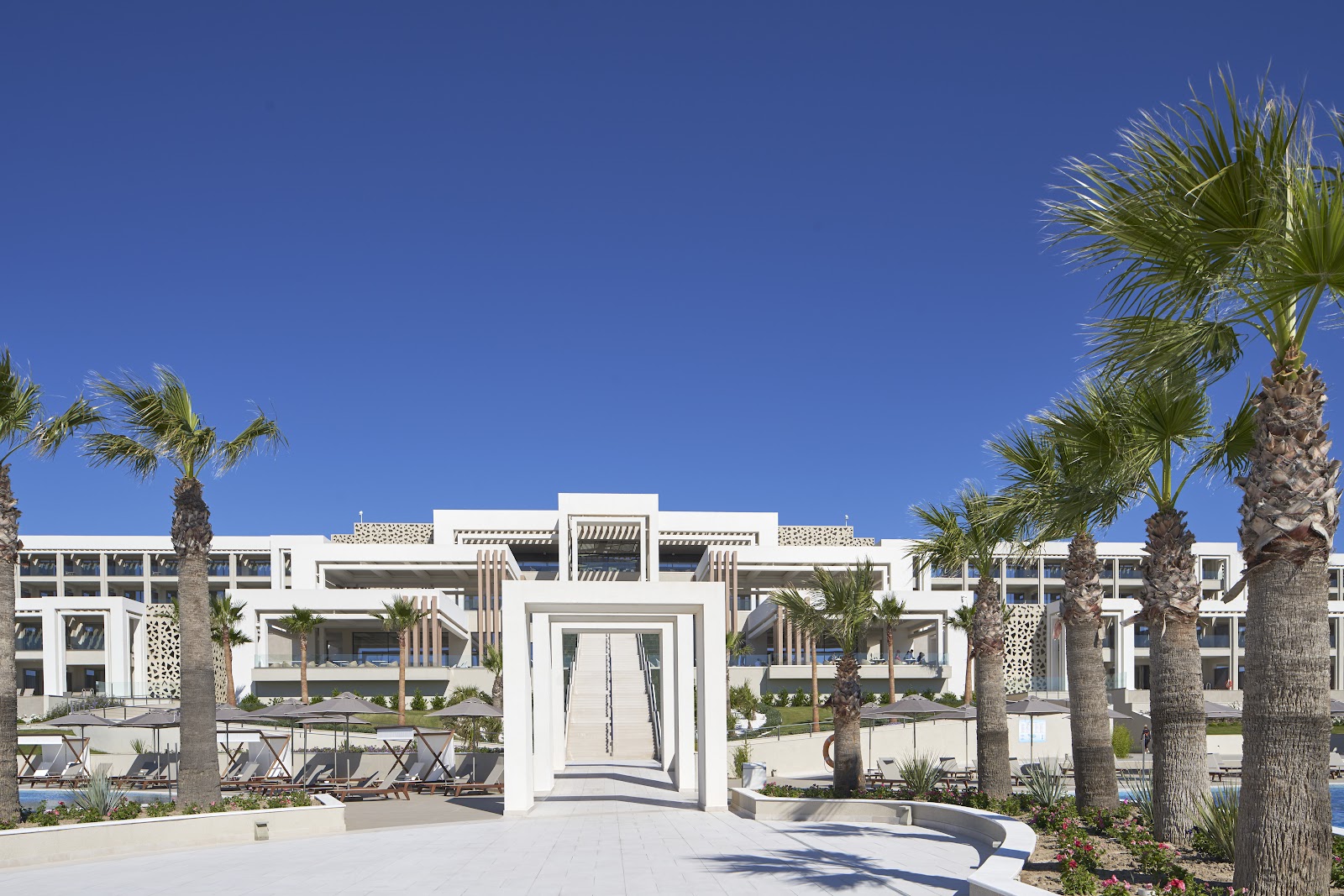 Indoor swimming pool at Mayia Exclusive Resort & Spa with illuminated water, marble columns, loungers, and geometric skylight panels in the ceiling.