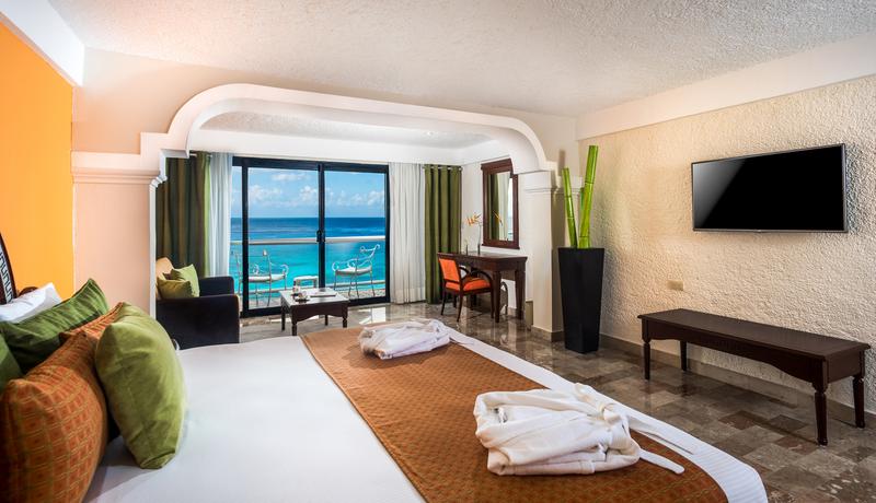 Beachfront dining pavilion with thatched roof, wooden support beams, striped chairs, and turquoise ocean views at Meliá Cozumel.