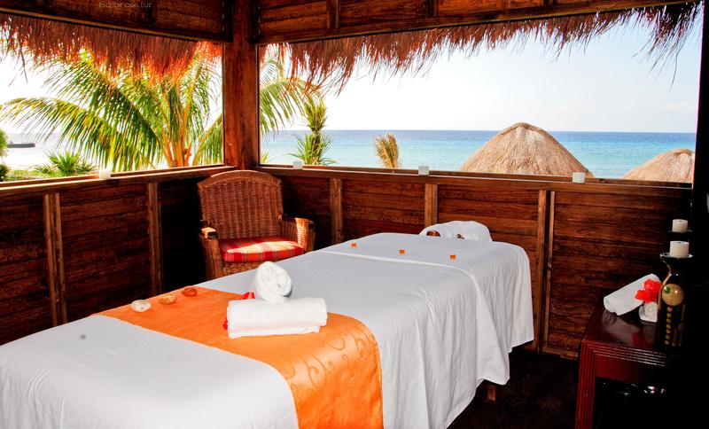 Sunset view at Meliá Cozumel with thatched umbrellas, loungers, and palm trees framing the ocean and colorful sky.