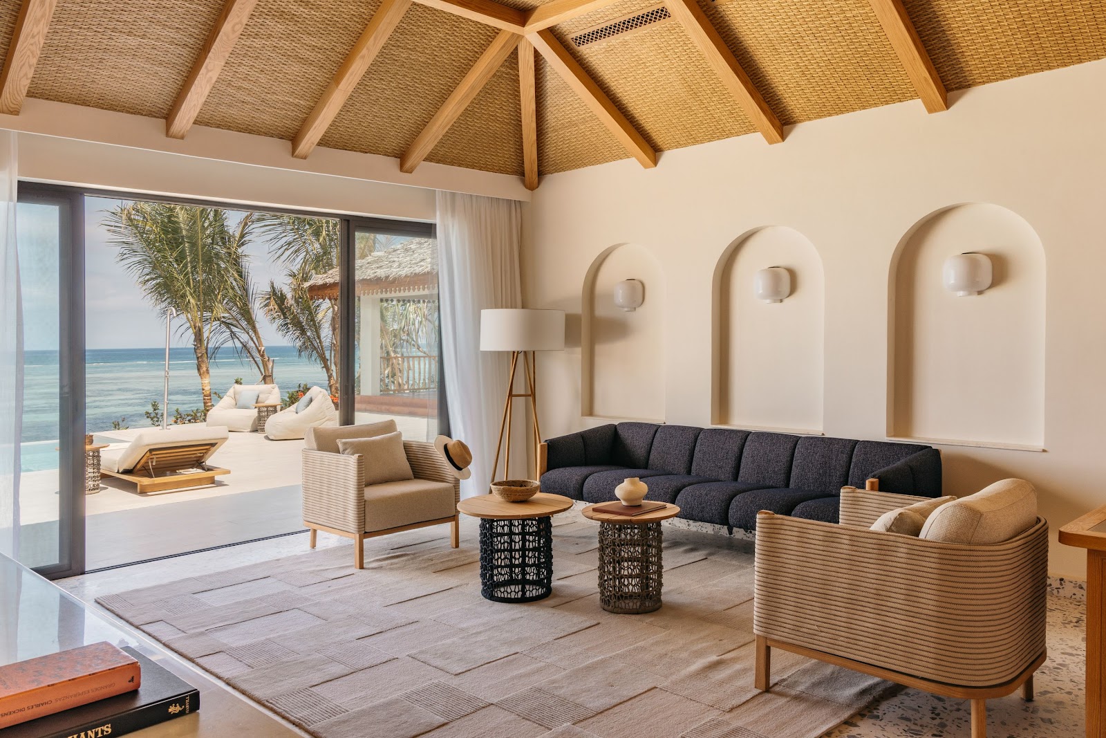 Modern beachfront villa with rectangular pool, purple umbrellas, and lounge chairs overlooking turquoise ocean and palm trees at Meliá Zanzibar.