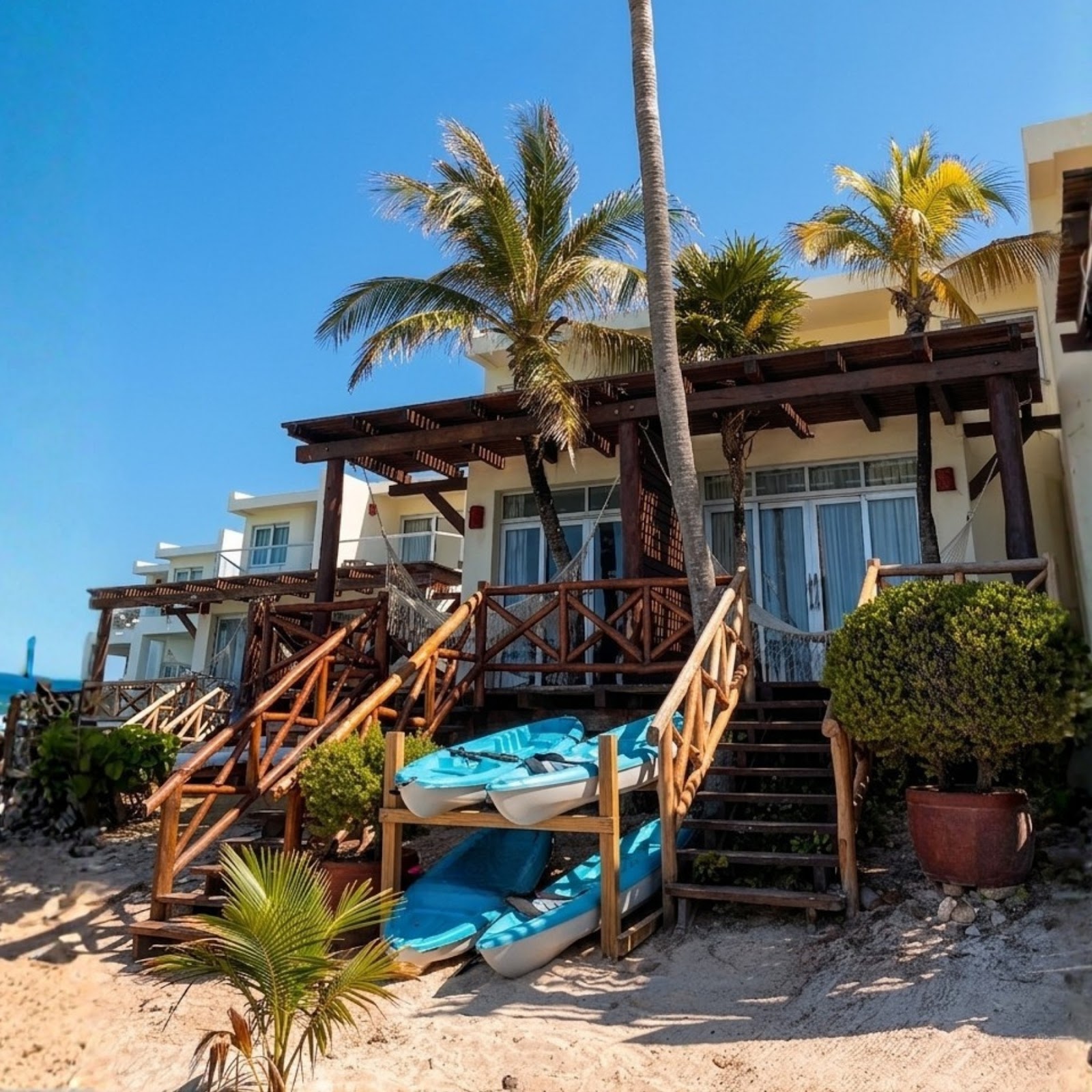 Wooden dock extending into turquoise water with sailboat, cruise ship, and thatched-roof barge visible at MIA Reef Isla Mujeres under clear blue sky.