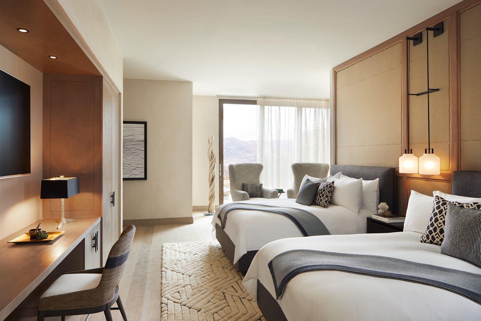 Modern resort suite with fireplace, cream armchairs, flat-screen TV, and access to adjoining room at Miraval Arizona Resort & Spa.