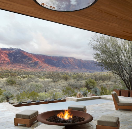 Modern fire pit with seating on a terrace overlooking desert landscape and red mountains at Miraval Arizona Resort & Spa.