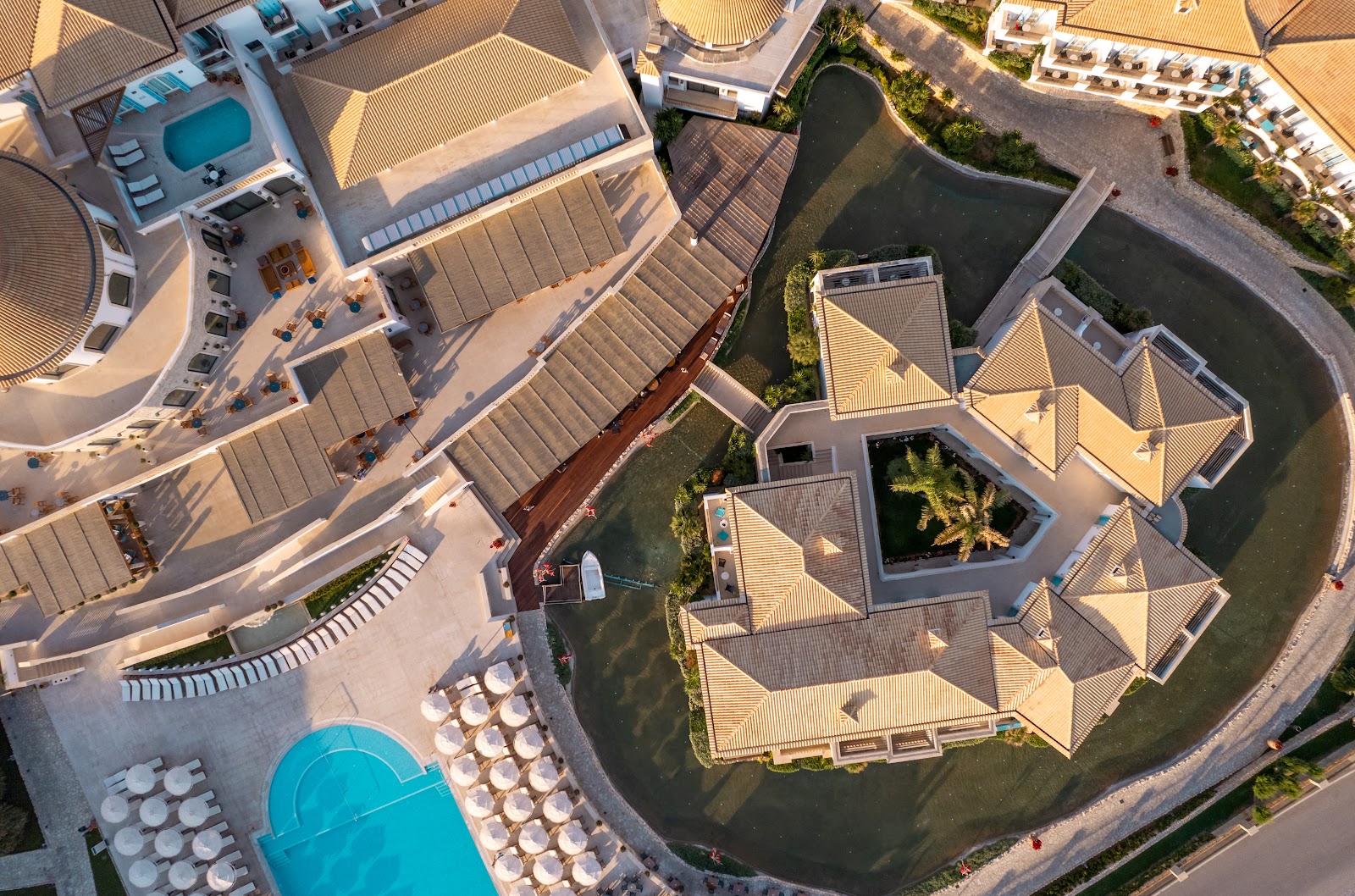 Aerial view of Mitsis Selection Laguna showing beige villa structures surrounding a lagoon with loungers and pools nearby.