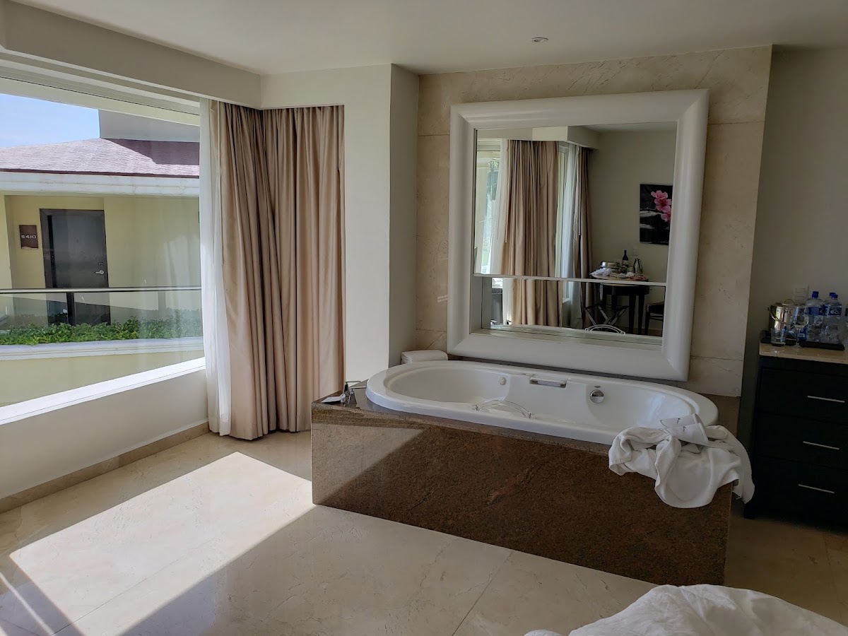 Resort suite bathroom with sunken soaking tub, large mirror, and window overlooking the resort grounds.