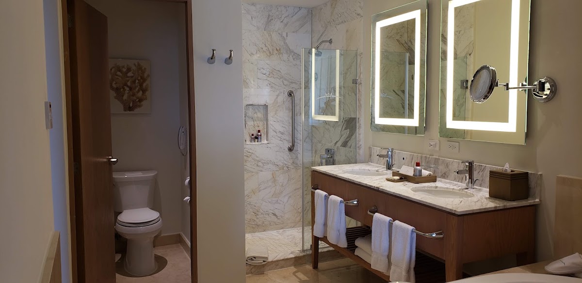 Bathroom with marble shower, dual vanity with lighted mirrors, and separate toilet room at Moon Palace Jamaica.