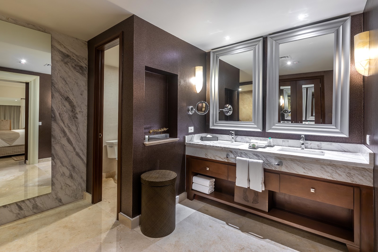 Luxurious bathroom with dual marble vanity, large framed mirrors, dark textured walls, and separate soaking tub at Moon Palace The Grand.