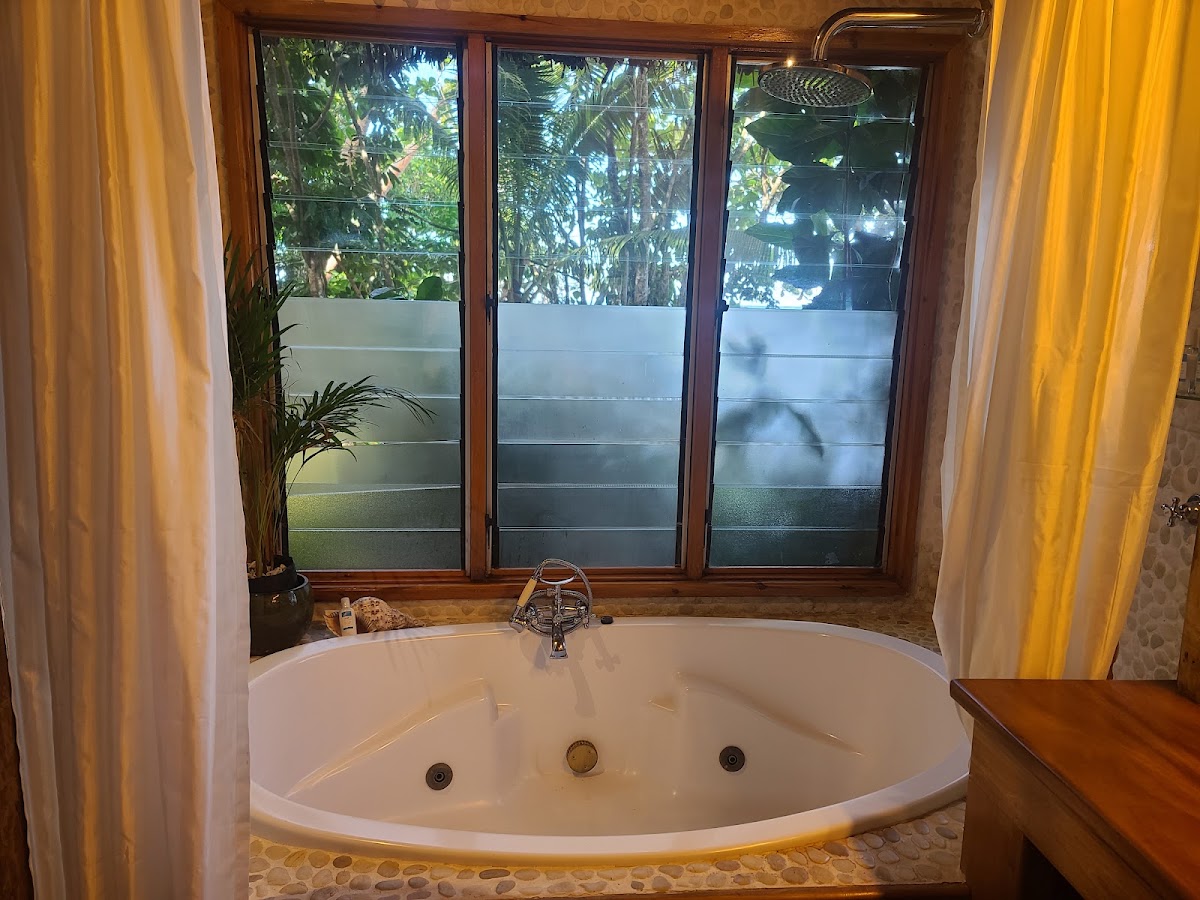 White soaking tub with jets below large windows overlooking tropical foliage at Namale Resort & Spa.