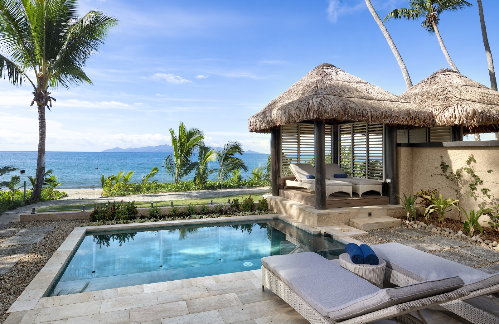 Private pool and thatched bungalow at Nanuku Resort Fiji overlook the ocean and palm-lined beach.