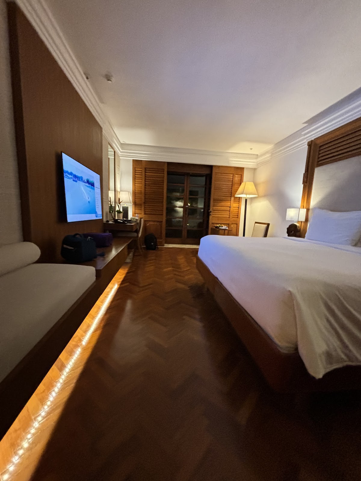 Spacious resort room with double beds, flat-screen TV, wooden louvered doors, and warm lighting at Nusa Dua Beach Hotel & Spa.