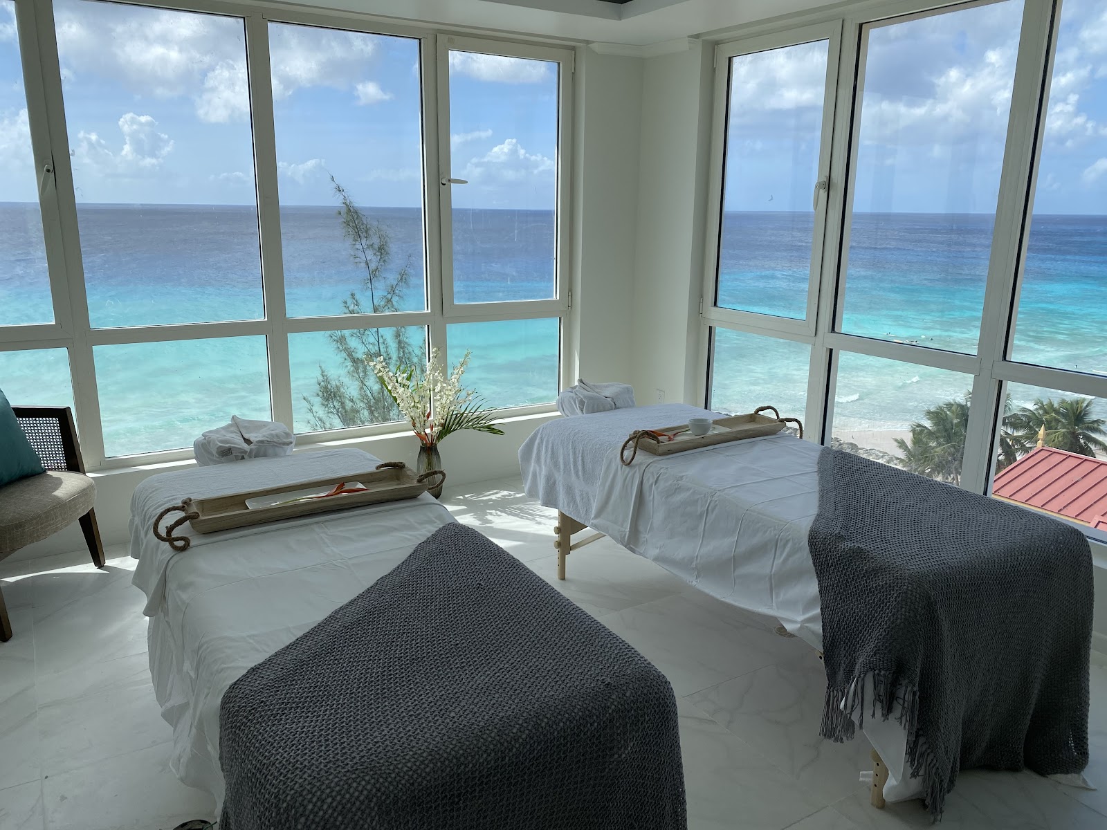 Spa treatment room with two massage beds overlooking turquoise ocean and beach at O2 Beach Club & Spa.