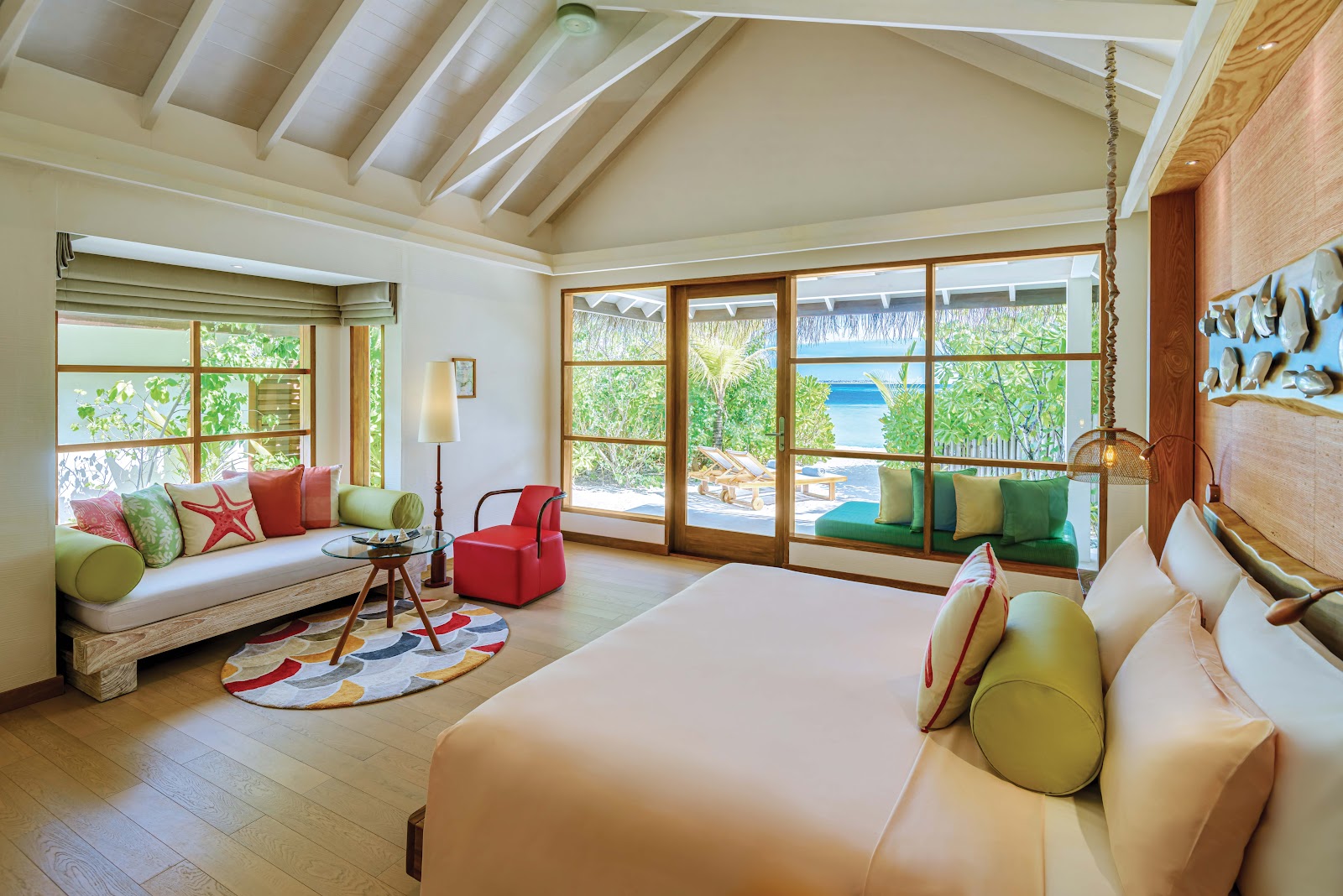 Spacious resort suite with bed, seating area, and large windows overlooking tropical gardens and ocean at OBLU SELECT Sangeli.