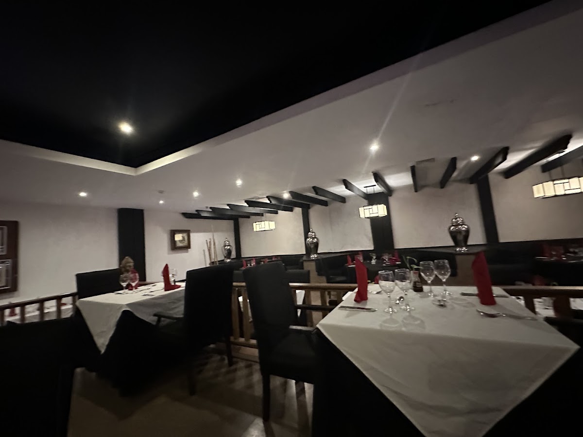 Modern dining room at night with white tablecloths, black chairs, red napkins, and black beam ceiling details at Occidental Punta Cana.