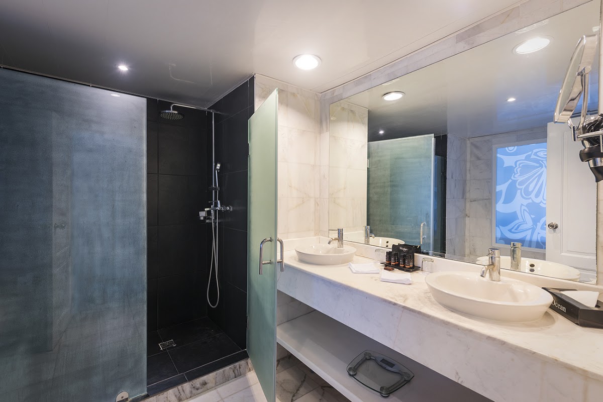 Modern bathroom with black walk-in shower, dual white vessel sinks, and large mirror at Ocean Blue & Sand resort.