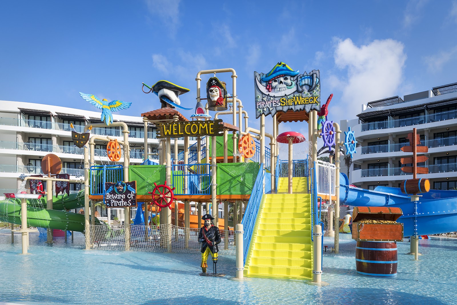 Pirate-themed water play structure with yellow slide and colorful decorations in shallow pool at Ocean Coral Spring resort.