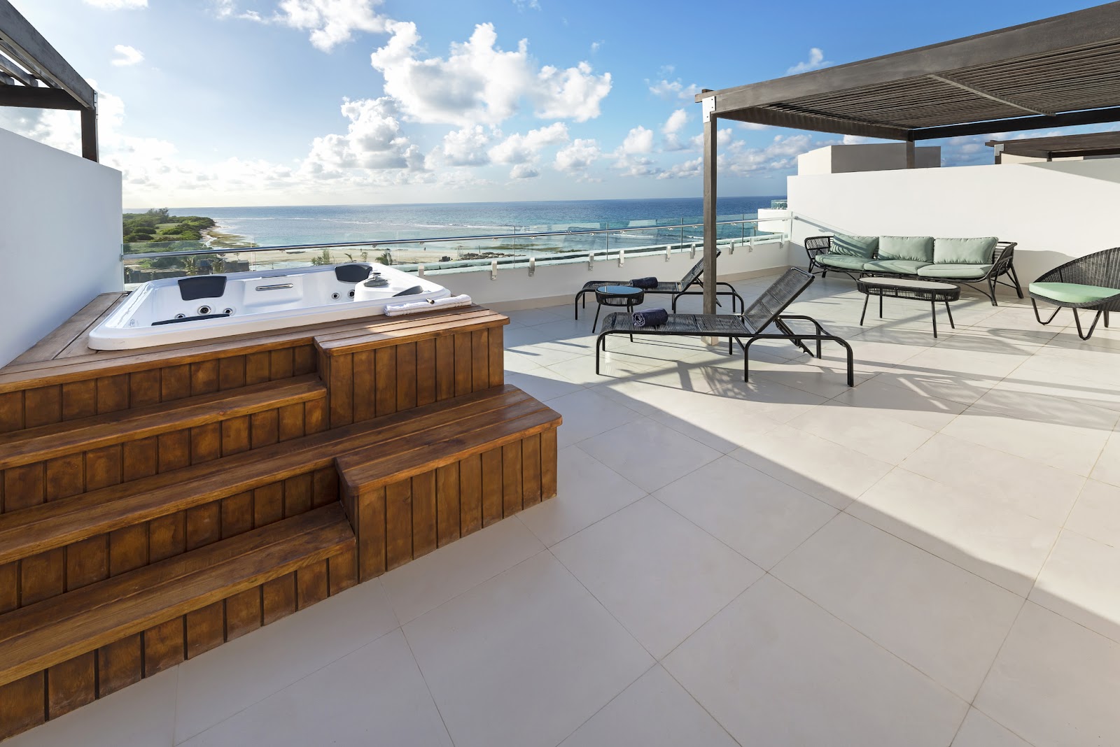 Rooftop terrace at Ocean Eden Bay with wooden bar, lounge seating, pergolas, and ocean view overlooking Jamaica's coastline.