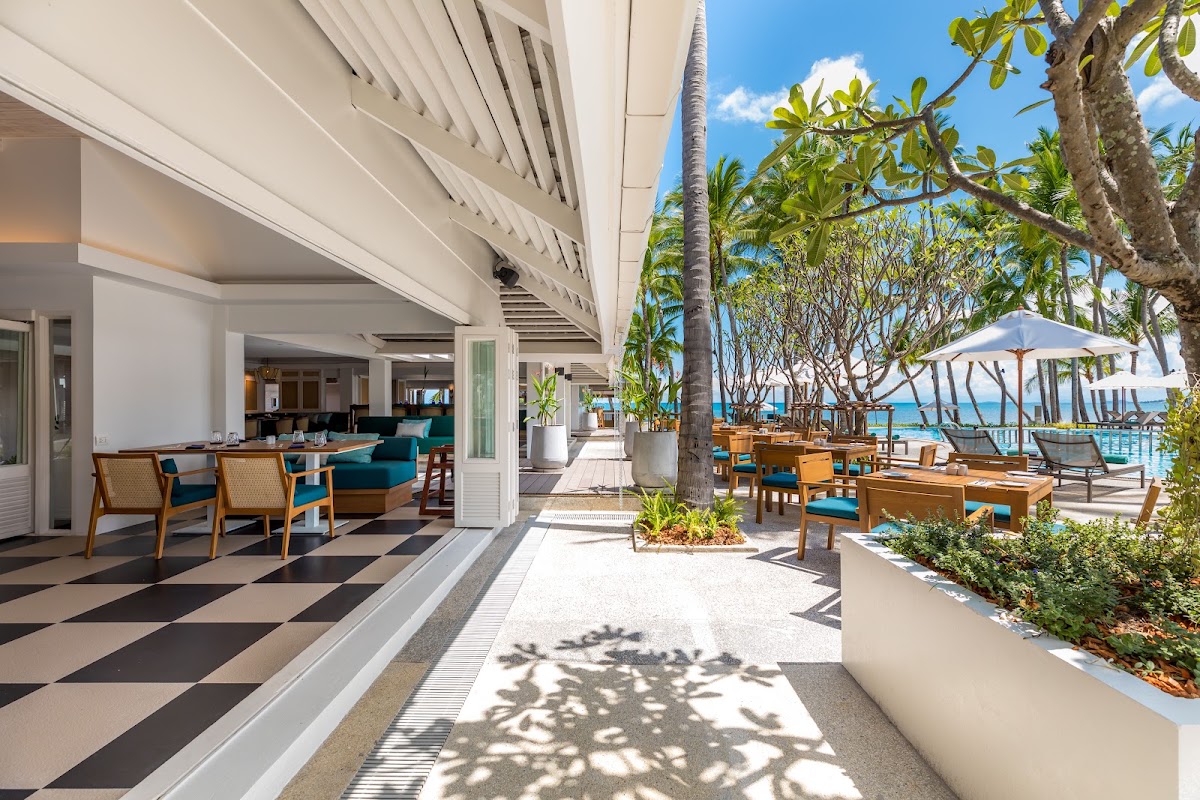 Modern resort terrace with lounge chairs, plumeria trees, and ocean views at OUTRIGGER Koh Samui Beach Resort.