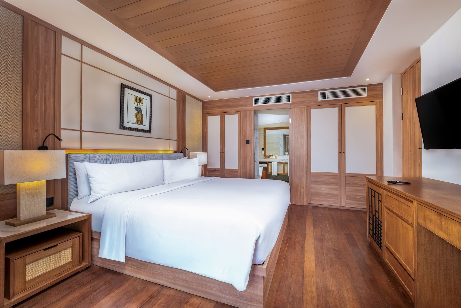 Resort bedroom with open doors overlooking pool, lawn, and beach umbrella at Paradisus by Meliá Bali.