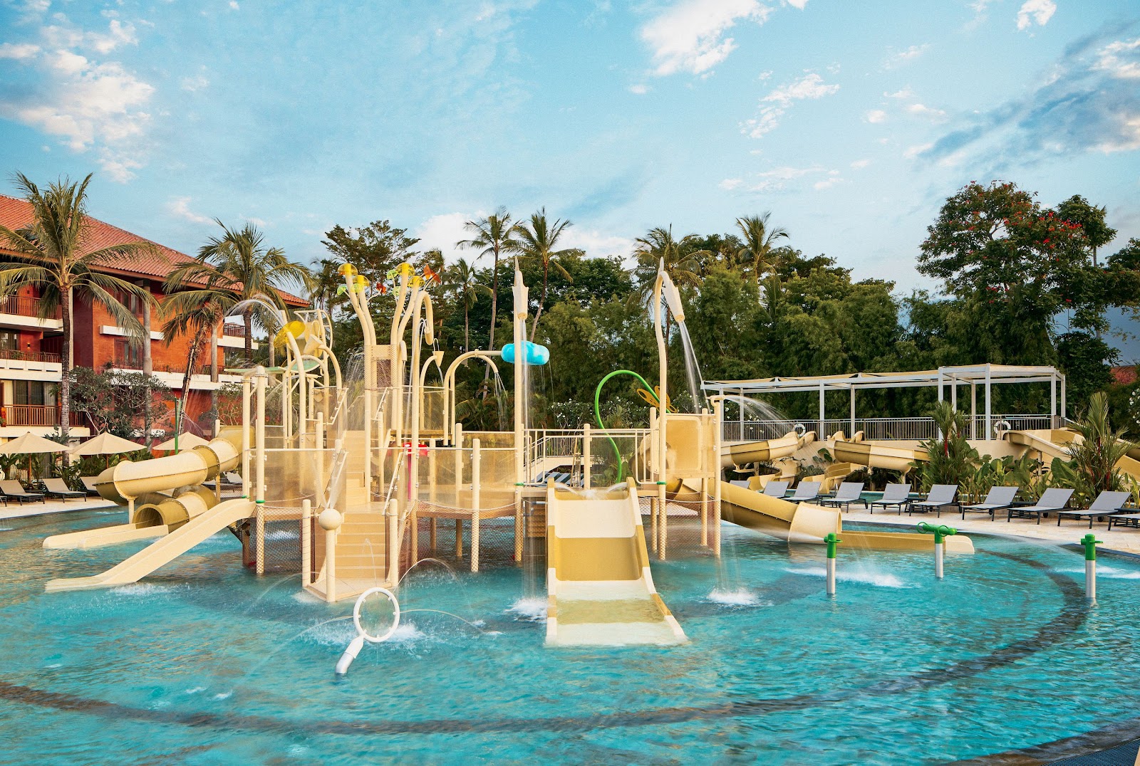 Children's water play area with multiple slides, tube slides, and spray features at Paradisus by Meliá Bali, surrounded by lush tropical vegetation under clear sky.