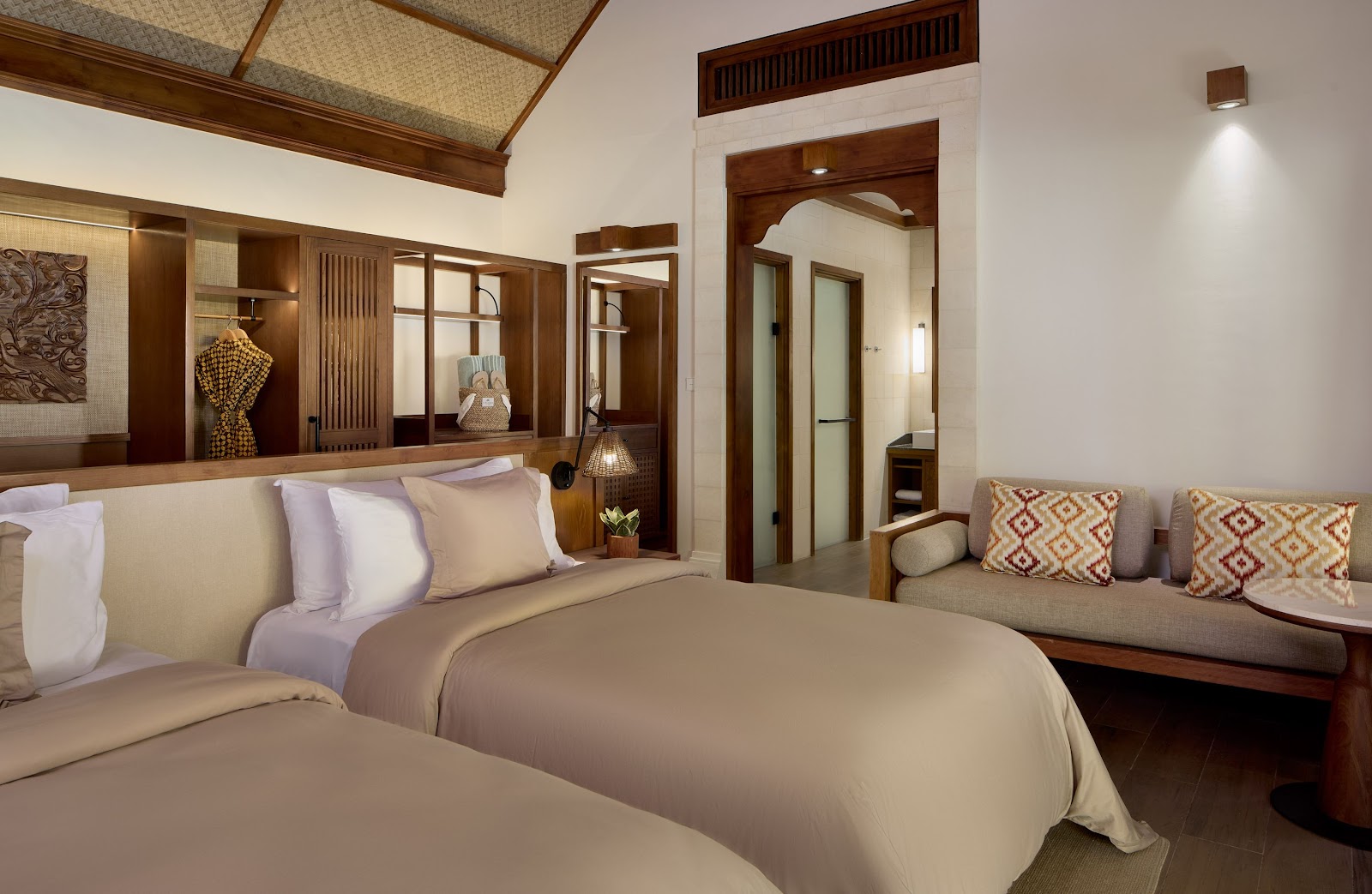 Paradisus by Meliá Bali courtyard with traditional red-tiled roof building, palm trees, manicured lawn, water channels, and stone fountains under clear blue sky.