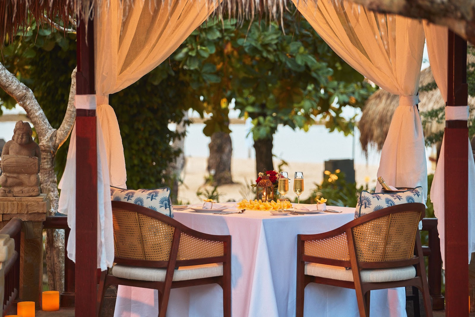 Magenta bougainvillea frames a wooden deck overlooking a sandy beach, calm bay waters, and forested coastline at Paradisus by Meliá Bali.