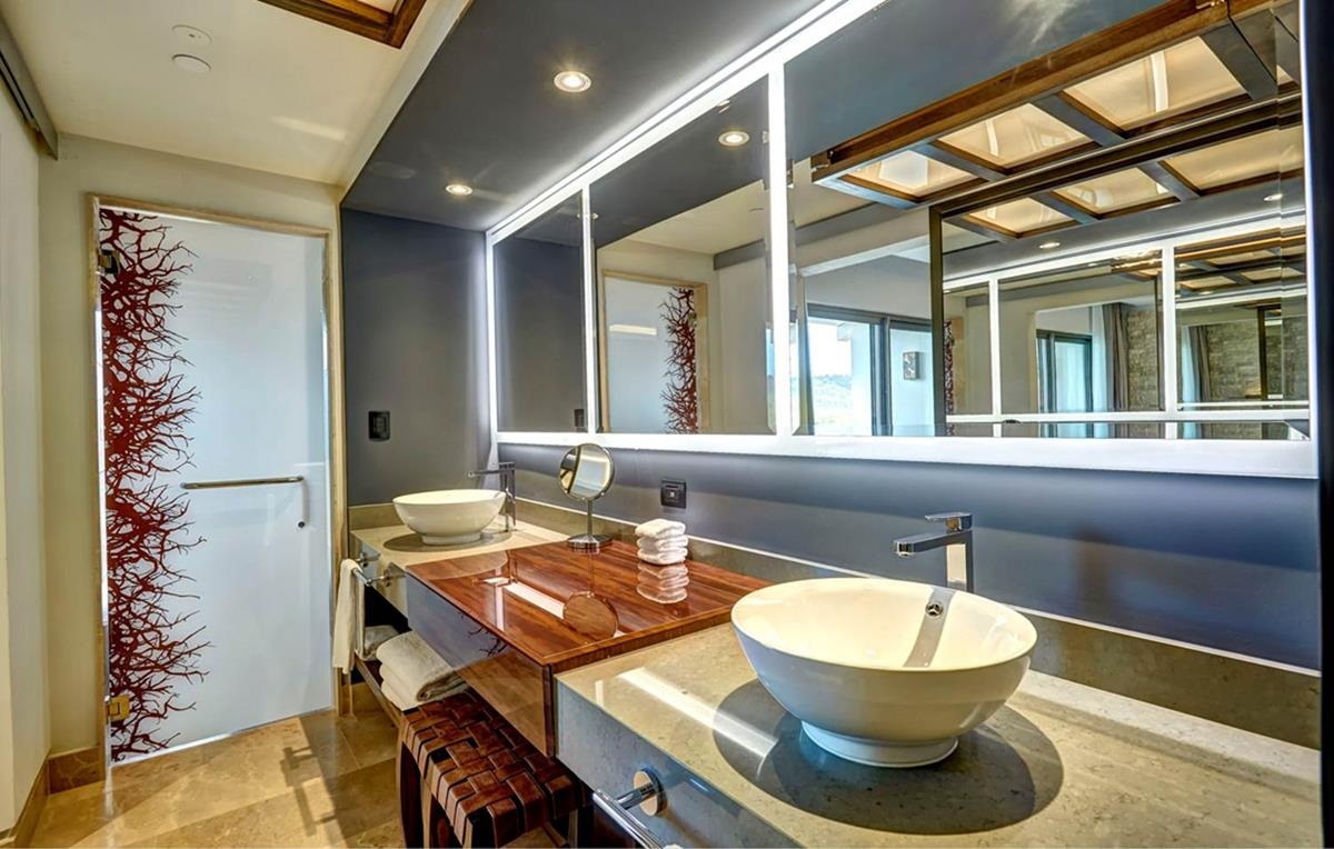 Modern bathroom with dual vessel sinks, illuminated mirrors, wood vanity, and gray tile accents at Planet Hollywood Costa Rica by Royalton.