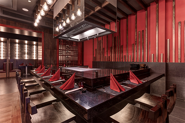 Modern teppanyaki dining room at Planet Hollywood Costa Rica with red walls, black tables, and chef cooking stations.