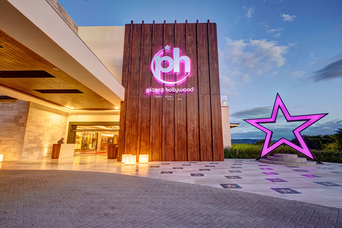 The Fuel cafe at Planet Hollywood Costa Rica features a purple-framed counter with marble top, orange chairs, pendant lights, and brick accents.