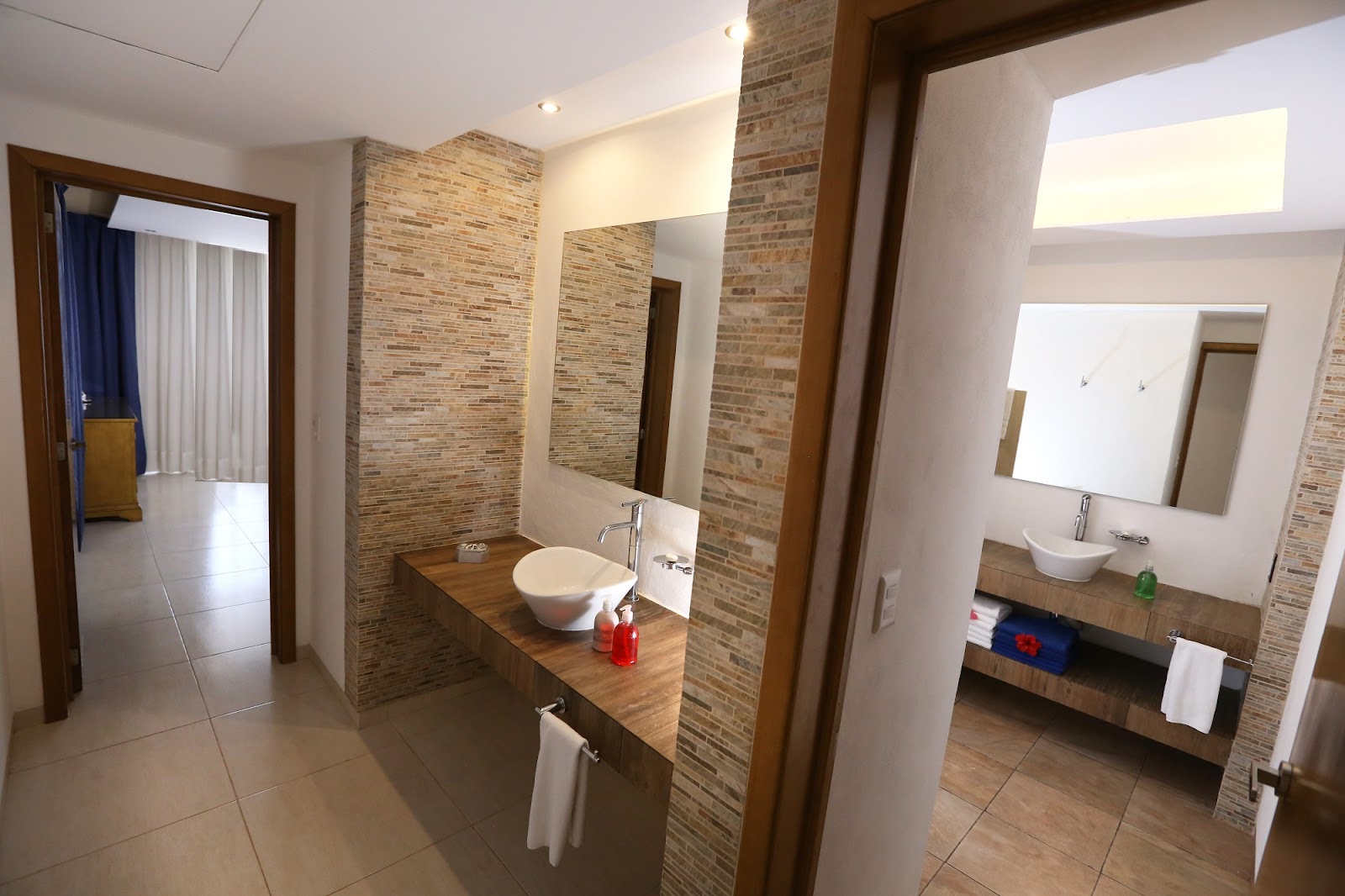 Spacious bathroom with brick accent walls, dual sinks, and wooden vanities at Playa Azul Cozumel Hotel.