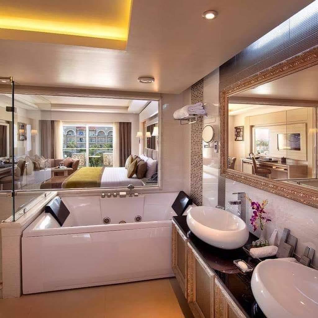 Luxury bathroom with soaking tub, vessel sink, and mirror overlooking bedroom with balcony view at Premier Le Reve Hotel & Spa.