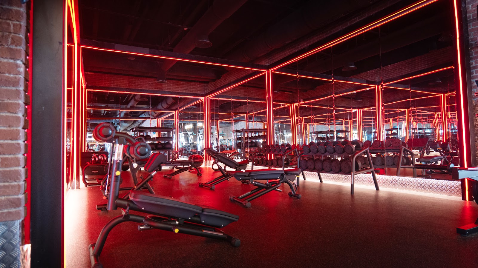 Fitness center at Princess Grand Jamaica with red neon-framed mirrors, exercise equipment, and red flooring.