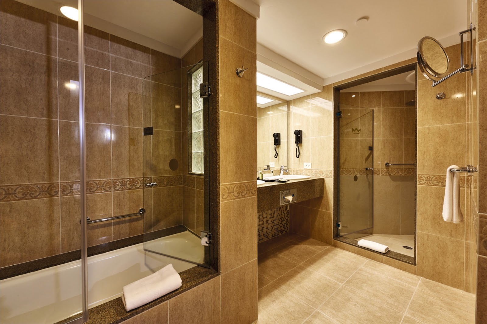 Spacious resort bathroom with brown tile walls, dual walk-in showers, vanity with mirror, and recessed lighting.