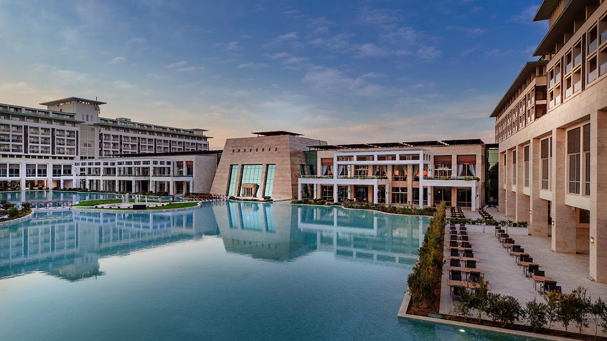 Turquoise lagoon pool reflects modern resort buildings with loungers lining the terrace at Rixos Premium Belek.
