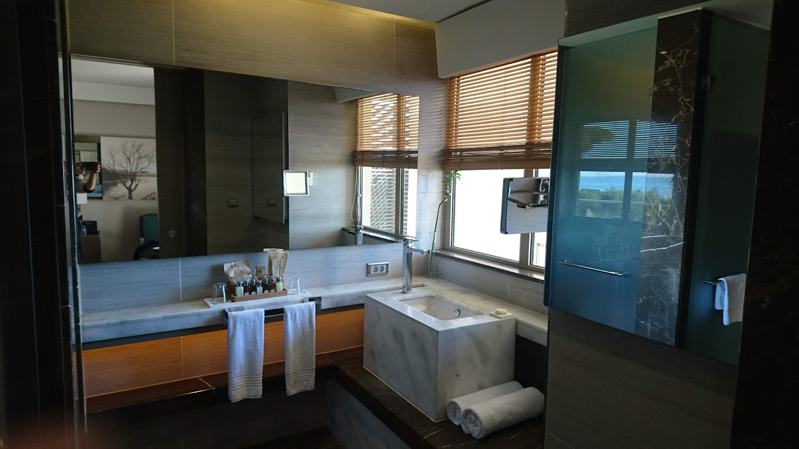 Bathroom at Rixos Premium Belek with dual vanity, soaking tub, and large mirror overlooking landscape views through wooden shutters.