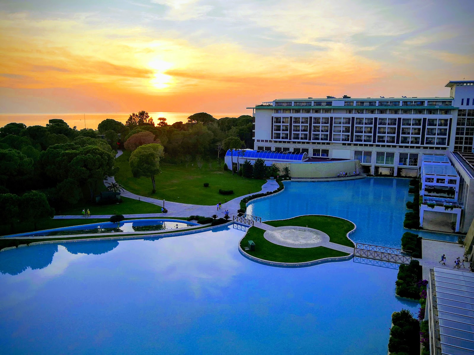 Rixos Premium Belek illuminated at night with blue-lit pool in foreground reflecting the modern multi-story building facade.