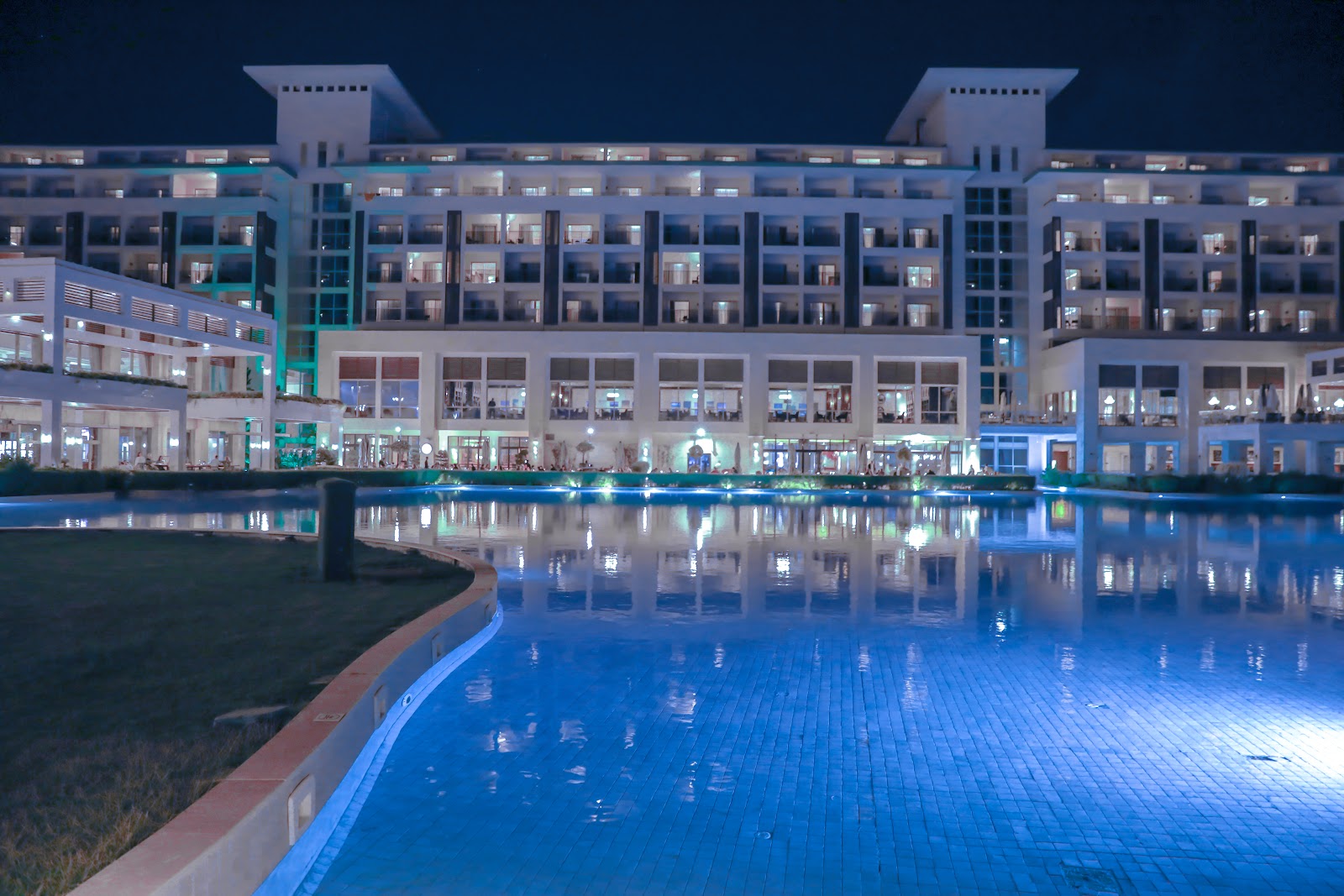 Rixos Premium Belek lobby atrium with skylight, ornate blue patterned floor, white columns, and balconies on multiple levels.