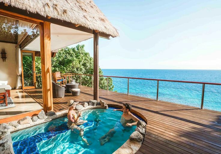 Guests swim in a private plunge pool on a thatched bungalow deck overlooking turquoise ocean water at Royal Davui Island Resort.