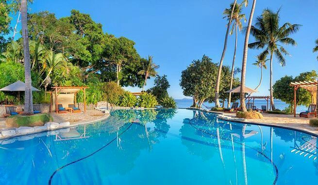 Large resort pool with clear blue water, palm trees, and ocean view at Royal Davui Island Resort in Fiji.