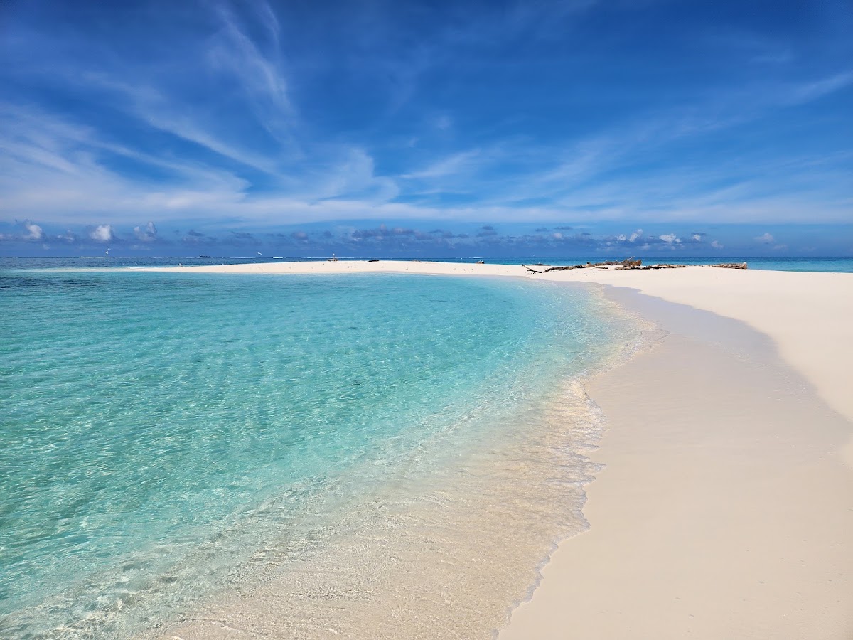 White sand beach and clear turquoise water at Royal Davui Island Resort with blue sky and distant islands.