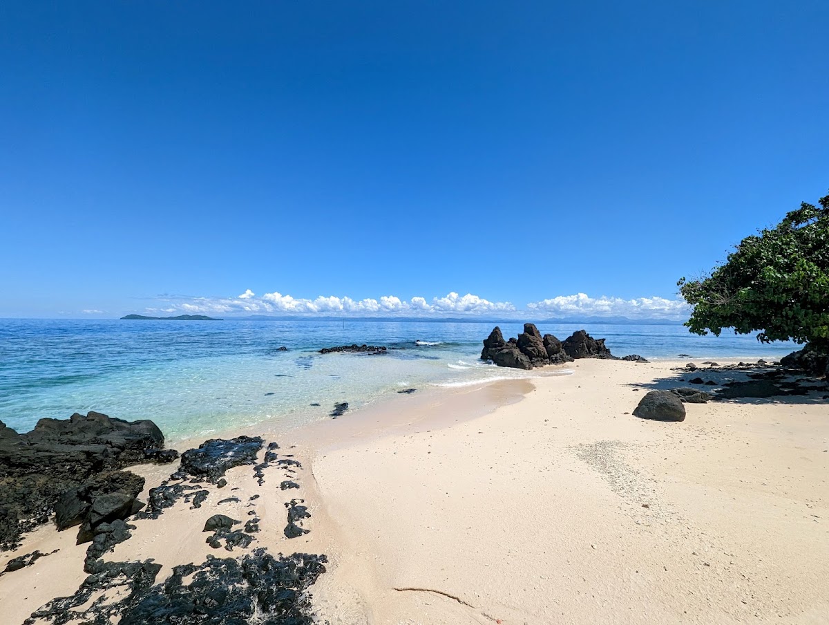 Sandy beach with rocky outcrops and turquoise water at Royal Davui Island Resort, with distant islands visible under blue sky.