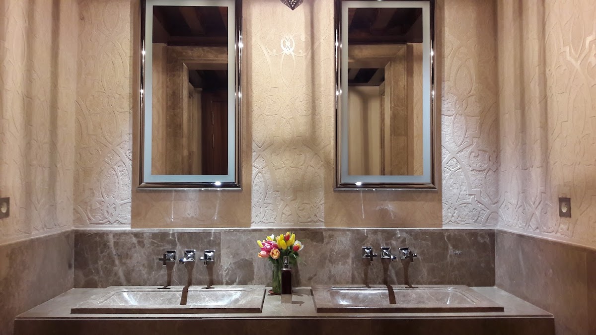 Marble bathroom with dual sinks, mirrored vanity, and fresh flowers in a vase at Royal Mansour Marrakech.
