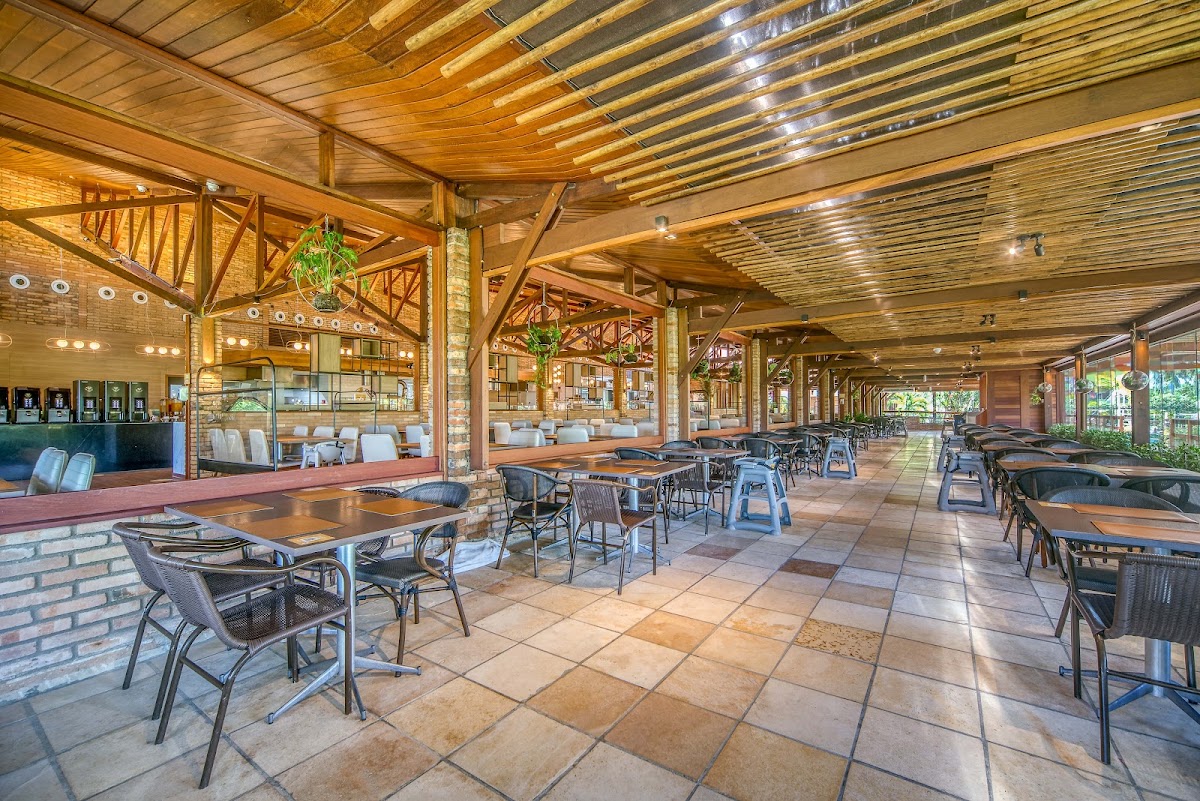 Spacious covered dining area with wooden beams, tile flooring, and metal-framed chairs at tables throughout the Salinas Maragogi All Inclusive Resort.