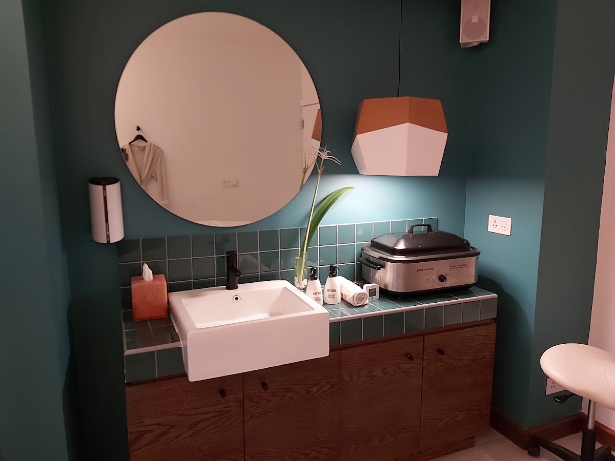 Modern bathroom with teal walls, white vessel sink, circular pink mirror, and dark wood vanity at SALT of Palmar.