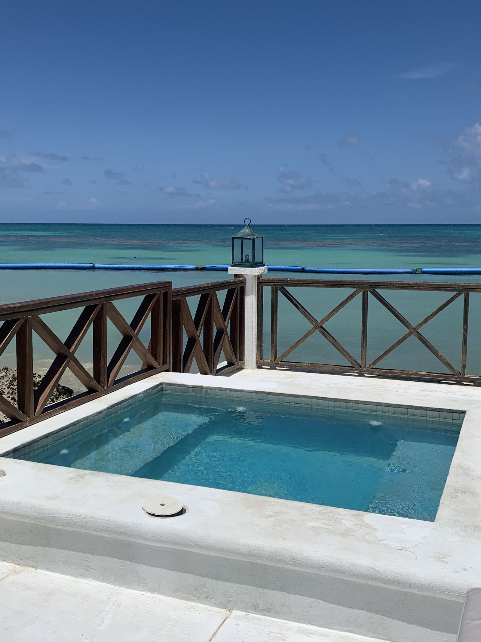 Sanctuary Cap Cana pool overlooking turquoise ocean with wooden railings and a lantern post on the pier.