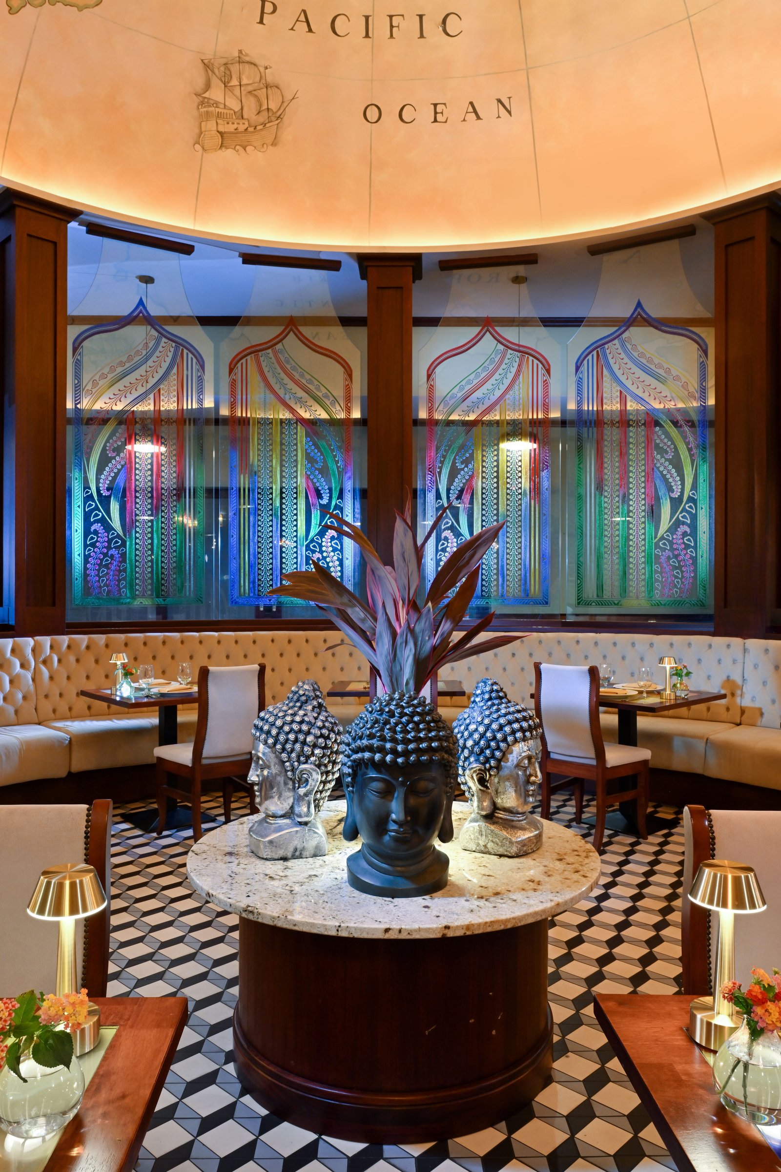 Bombay Club dining room with Buddha-head centrepiece and stained-glass panels.