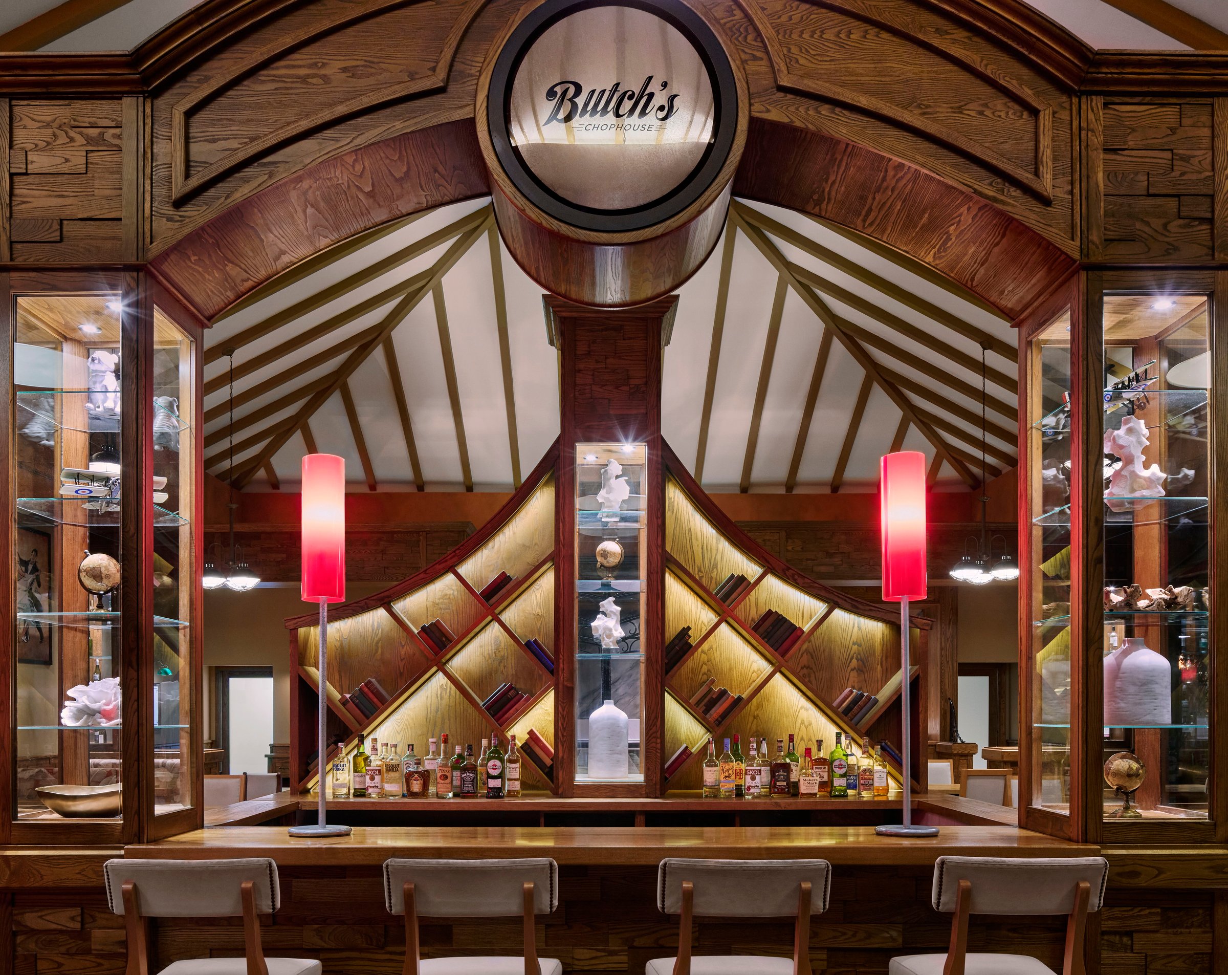 Butch's Chophouse bar with a backlit wine display and red lamps.