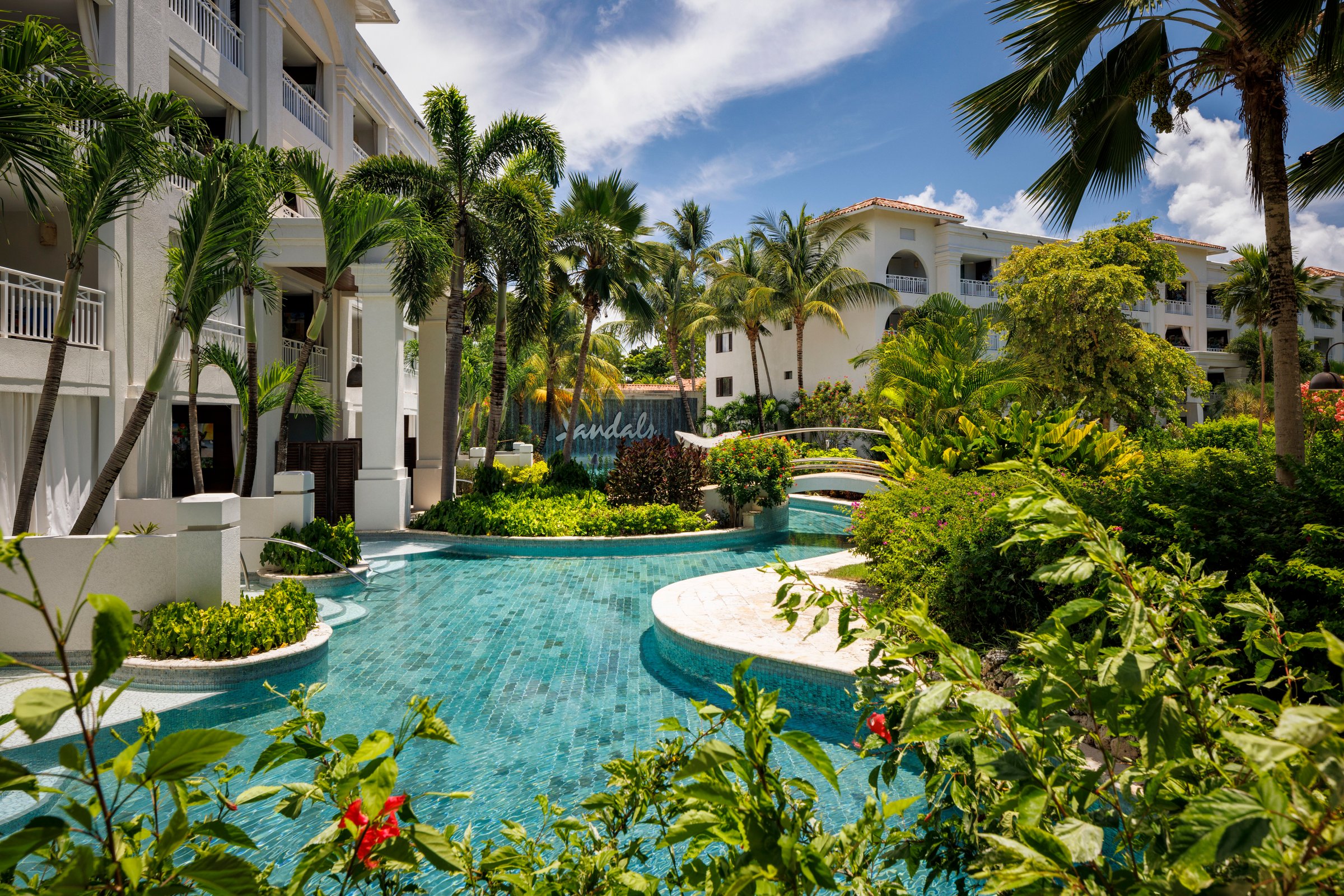 River pool winding past the swim-up suite block through lush tropical planting.