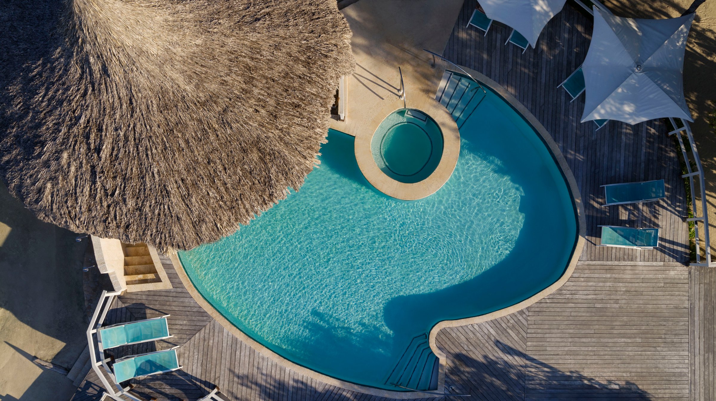 Overhead view of the island pool beside a thatched palapa.